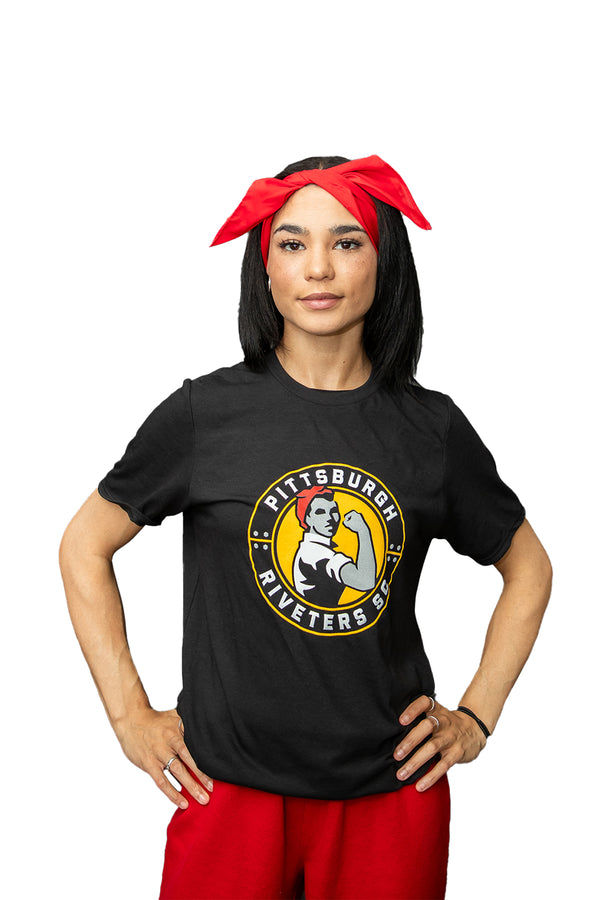 A person wearing a black T-shirt with 'Pittsburgh Riveters' logo and a red bandana tied around the head.